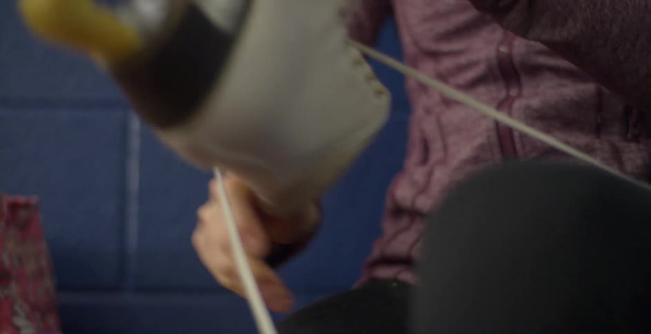 A woman lifting her leg to put on an ice skate