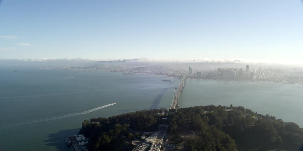 Aerial view of cars driving across a bridge in to a downtown area