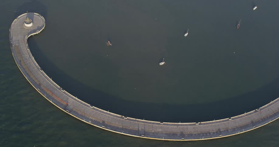 A concrete bridge stretches out into a body of water