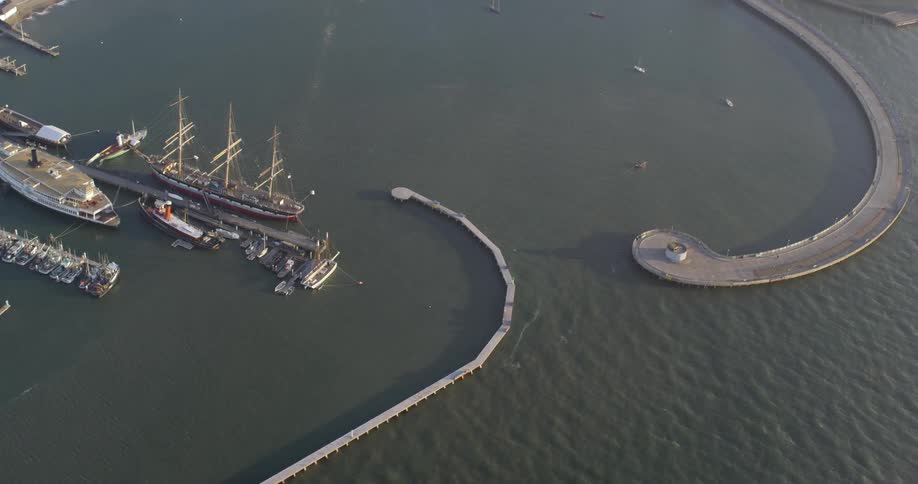 A concrete structure forms a barrier around a small bay containing a port