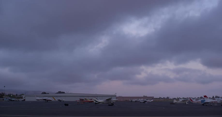 Small planes parked at a rural airport on a cloudy day