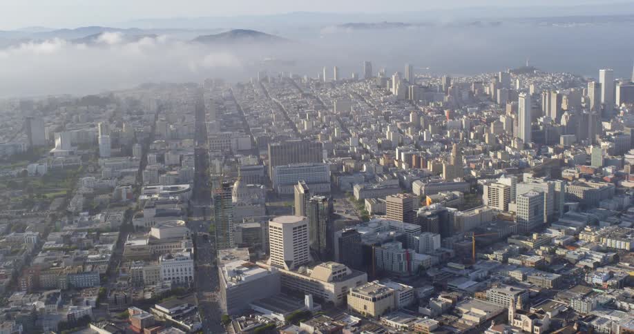 Fog starts to spread from a mountain range to a downtown city