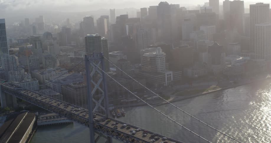 Aerial view of cars driving across a bridge into a downtown area