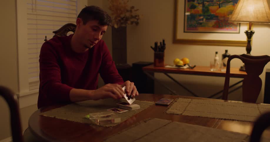 Man sits at dining room table playing solitaire near window