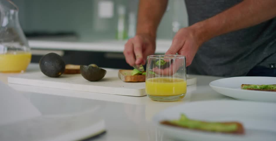 Close up of man spreading avocado on toast for breakfast