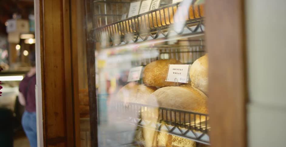 A store has bread piled in racks behind glass