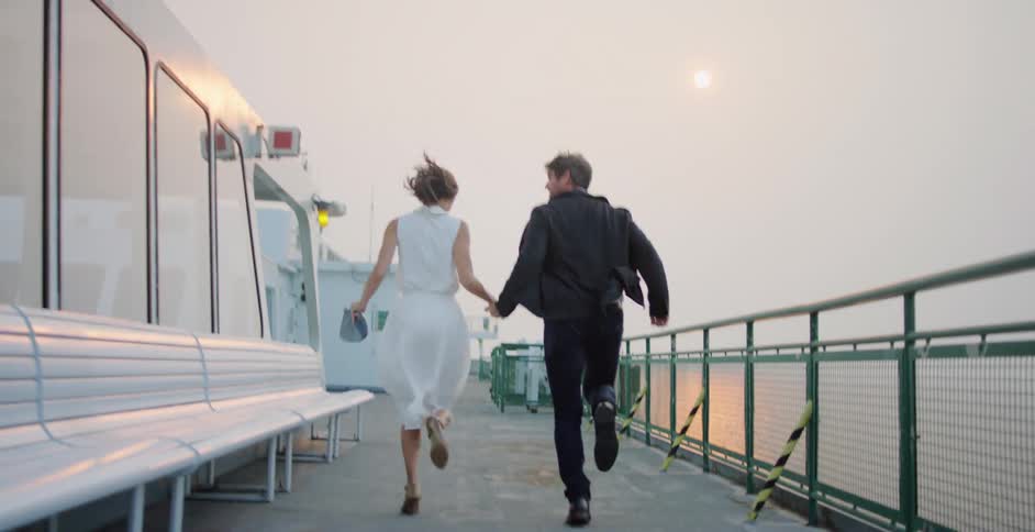 A man and woman hold hands running on the ferry