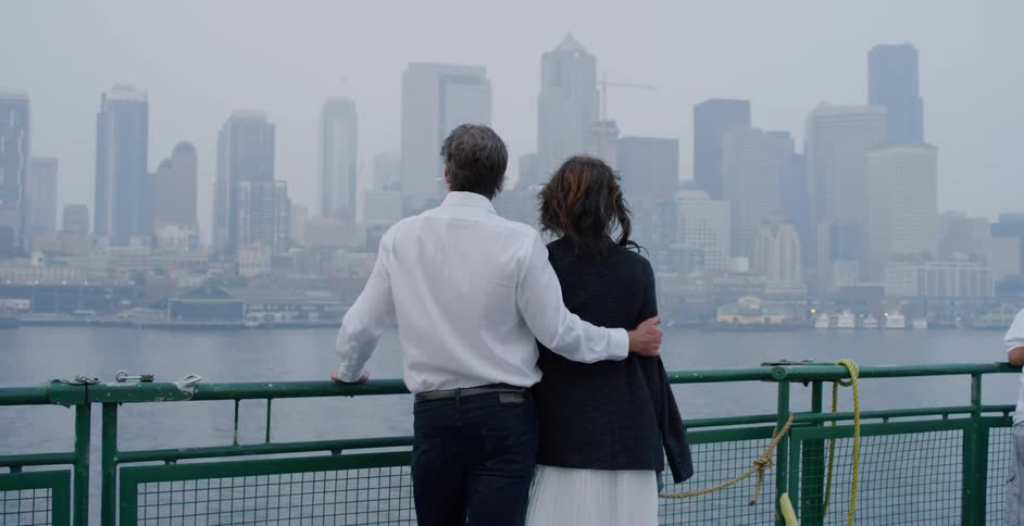 A man and woman standing and looking across the water at the city skyline