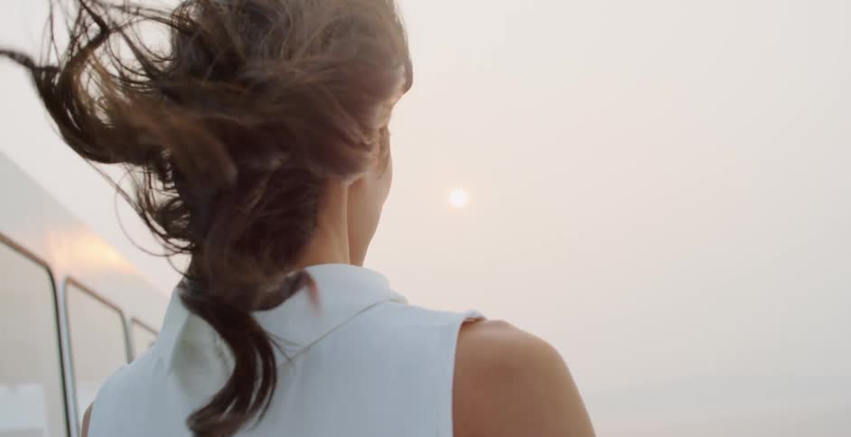 Womans hair blows in the wind as she stands outdoors