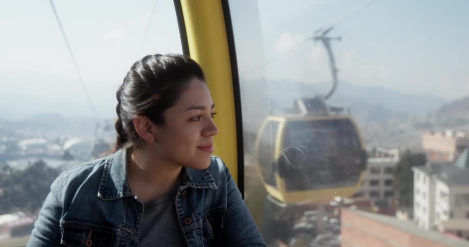 Smiling woman looks out of the window of a cable car in the city