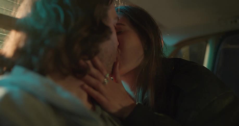 A teenage girl holds her boyfriends face as they kiss