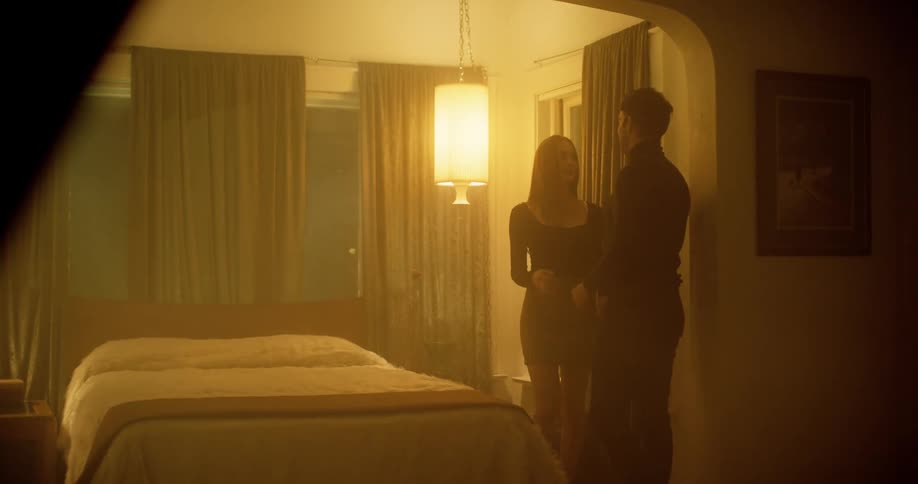 Blonde woman and man with a black turtleneck sweater makes out in the bedroom