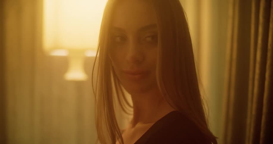 A white woman turns around in a room and smiles as she walks off