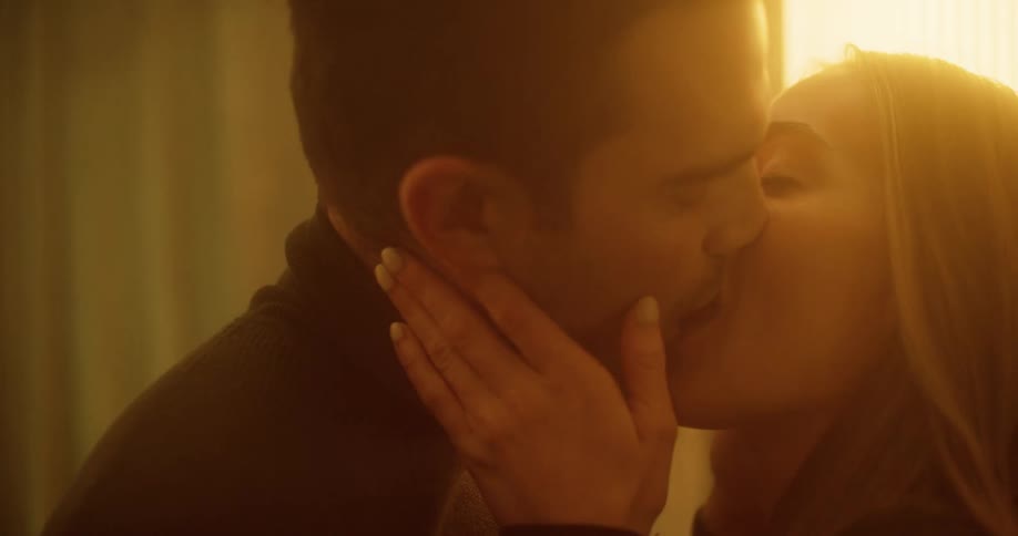 Couple stand near window touching and kissing