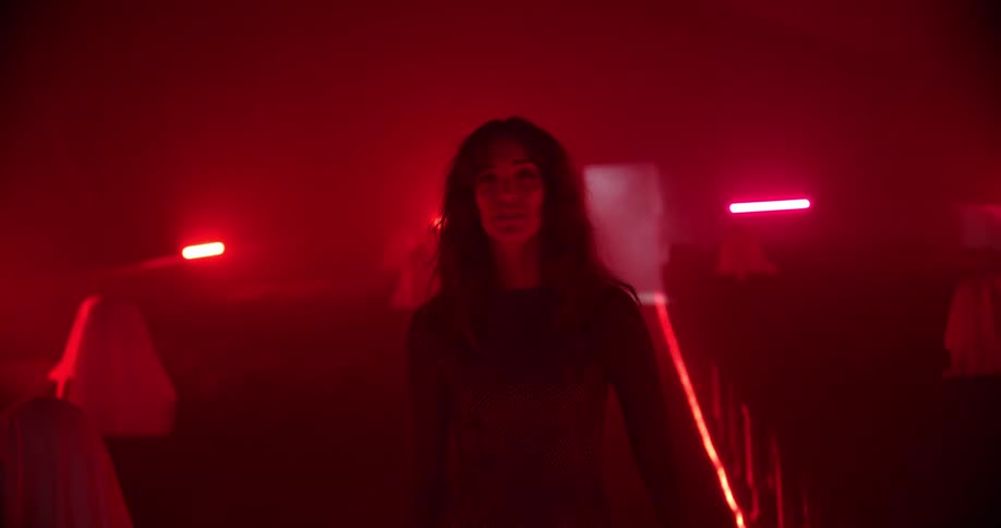 Woman wearing a long dress walks on a movie theatre under red lights