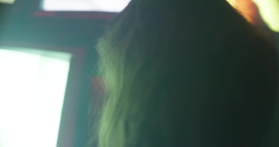 A woman singing in front of tv screens while touching them