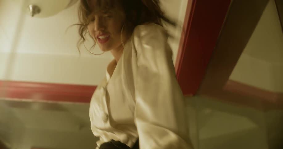 A woman dances in front of mirrors in a very small interior space