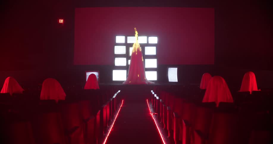 Fire burning on the stage of a theatre in front of tv screens showing static