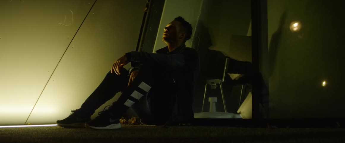 Man sits on floor leaning against reflective window