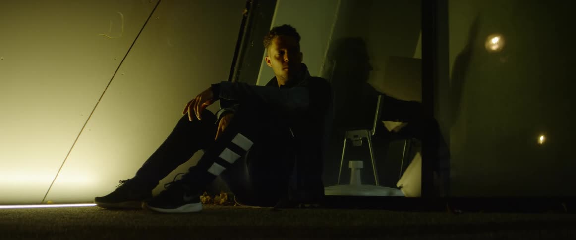 A young man sits with his back to some glass