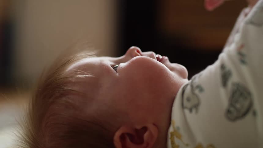 An infant lies on the floor and looks around