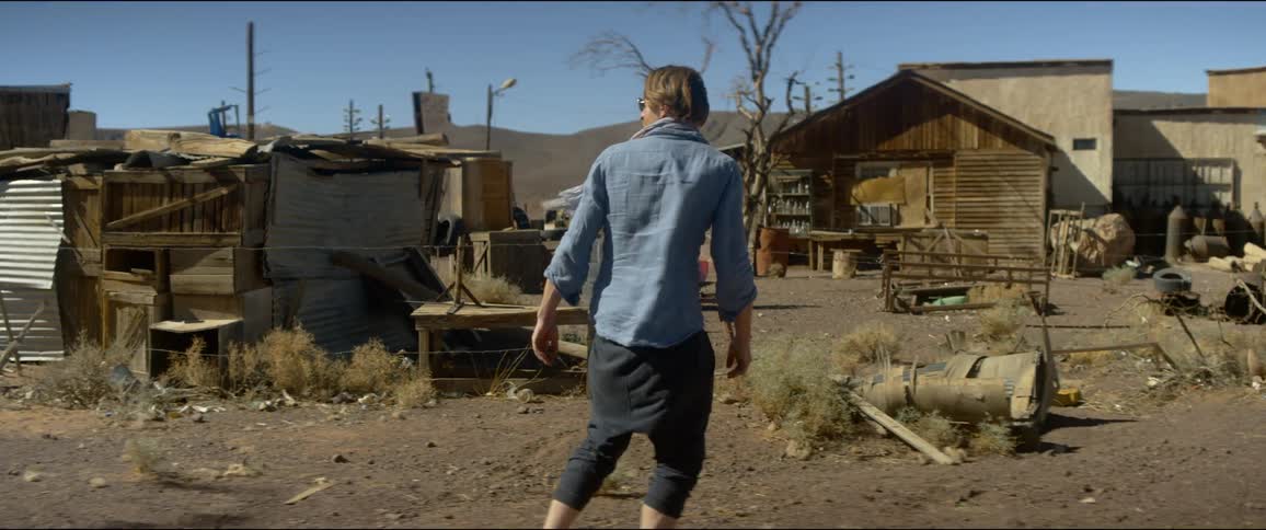 A man walks by a deserted small town village and weathered building