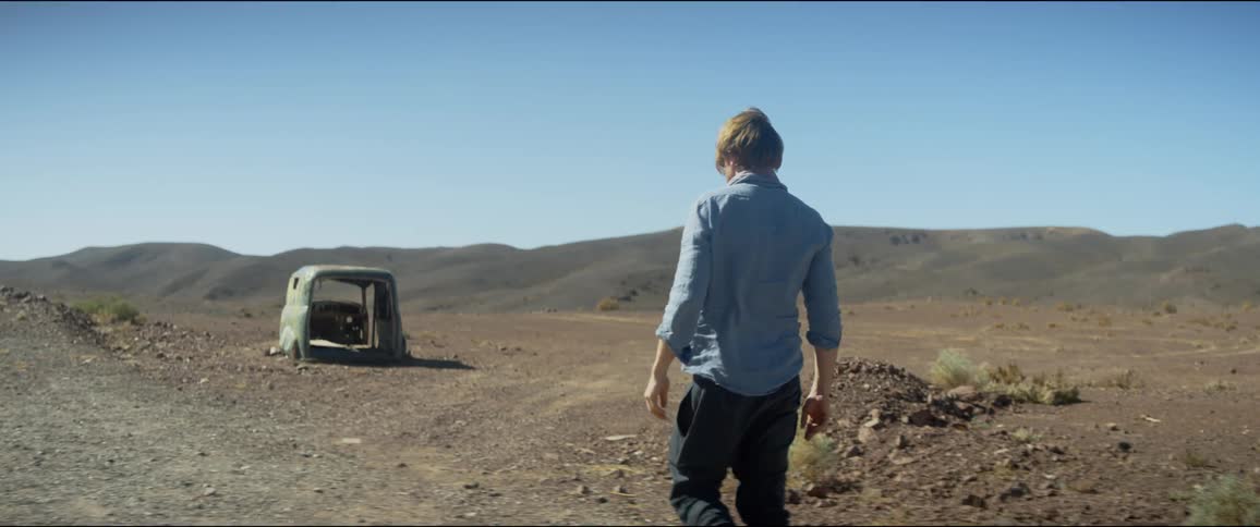 Man walks towards a tent in the desert under a blue sky