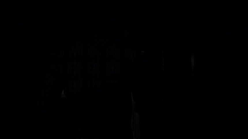 Long haired man walks down a dark corridor