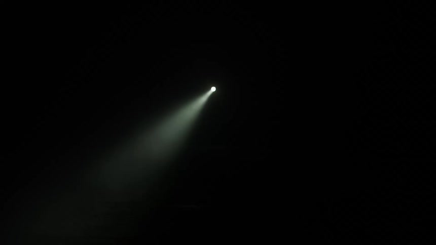 Beam of white light from a flashlight moves around a pitch black enviroment