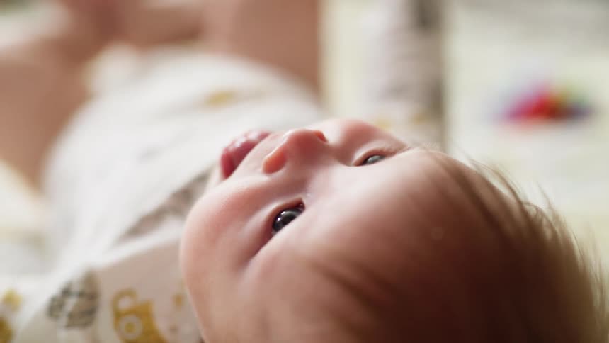 Baby laying in bed turns over his back
