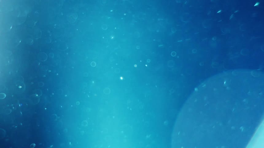 Light shines and glares as bubbles swirl and float on a blue background