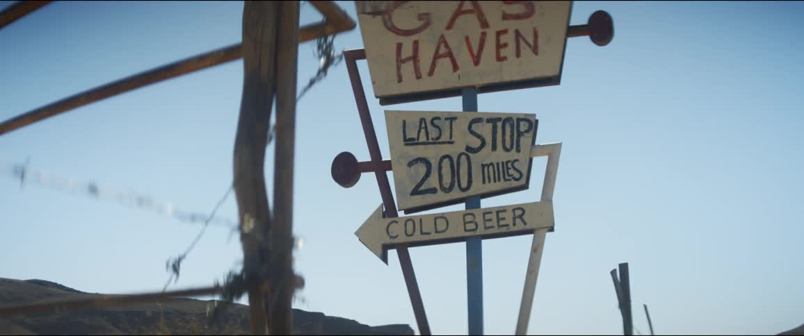 An old hand painted sign of a gas station in a desert on a sunny day