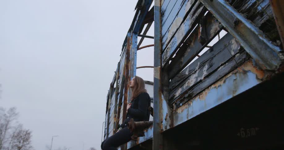 A young woman sits on an abandoned train