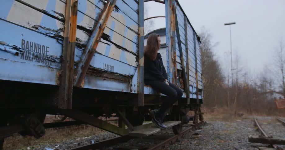 Woman sitting in an abandoned wooden railroad car