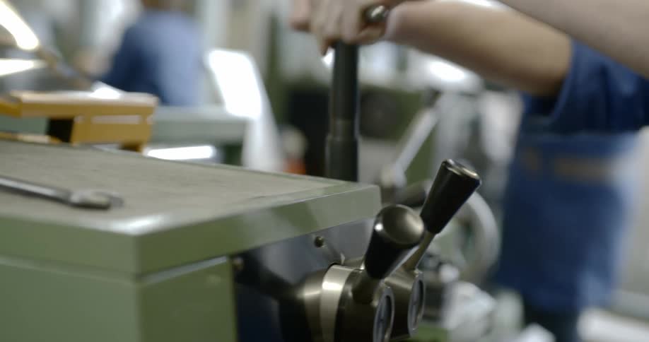 A worker turns a lever in a machine