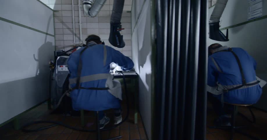 Several people are sitting in booths welding