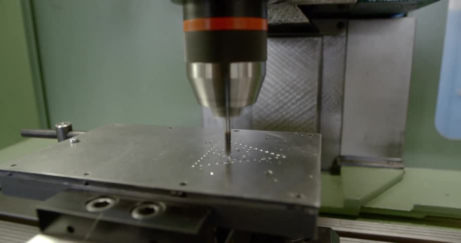 A machine engraves a triangle design in a piece of metal