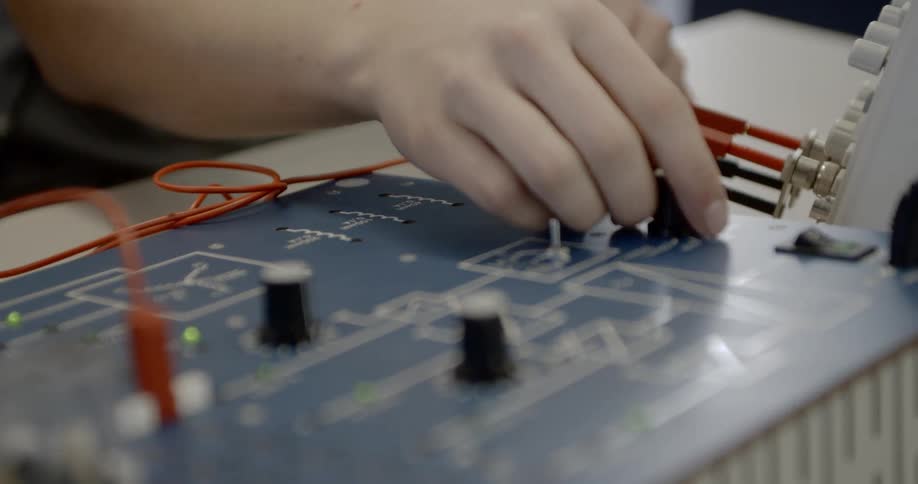 A man turns on a knob on a circuit board
