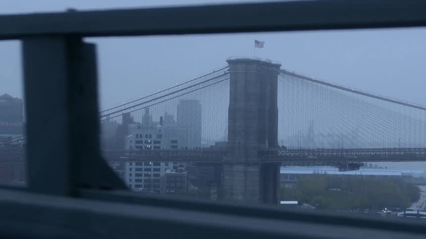 Light mist covers suspension bridge near boat and city that paralleling road