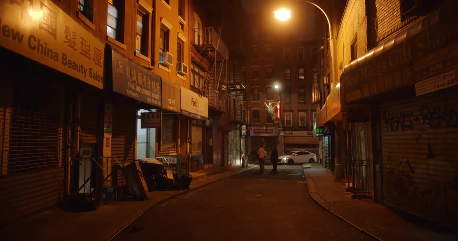People stand in the middle of a neighborhood street as a car turns in