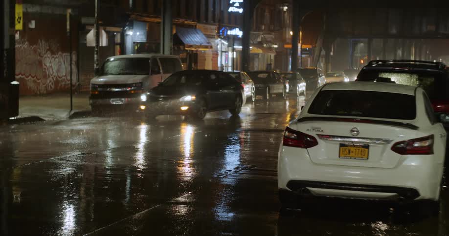 A city street with vehicles at night while its raining