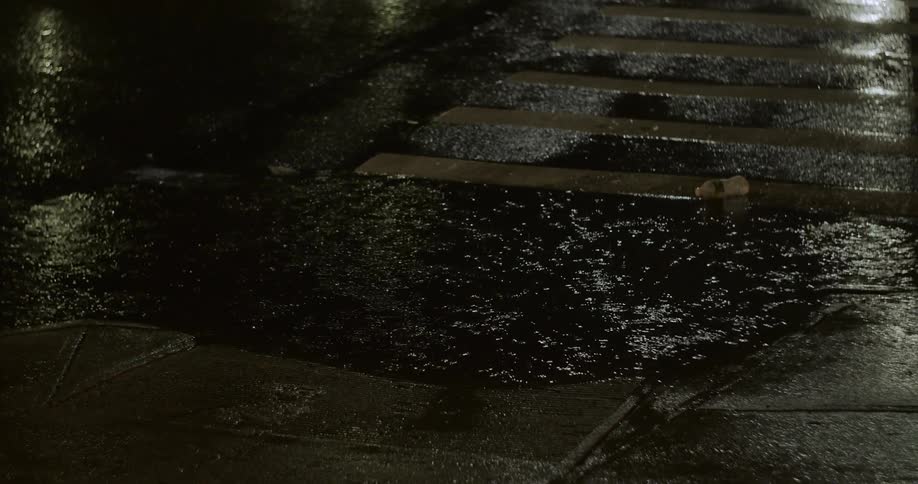Heavy rainfall forms a wide puddle on a cobblestone road