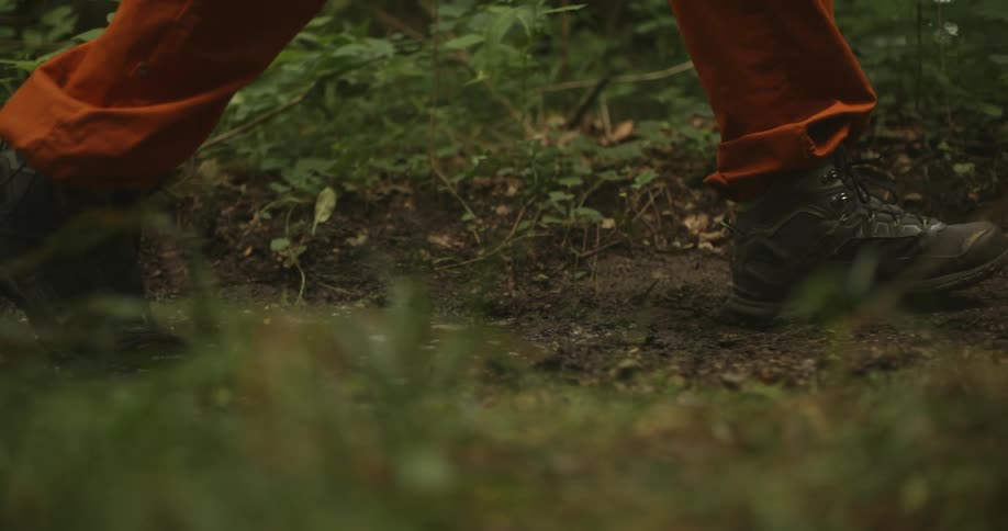 Two people wearing boot walk on a muddy dirt road