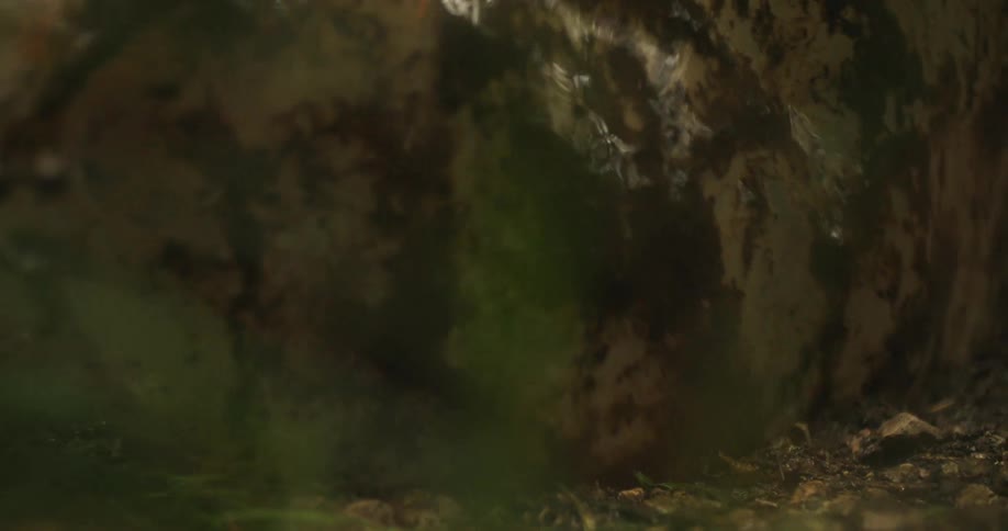 A person with boots stepping in a muddy puddle splashing mud and water