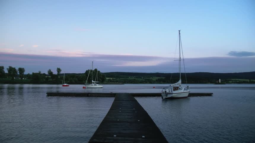 Sailboats float near dock with low mountains on horizon