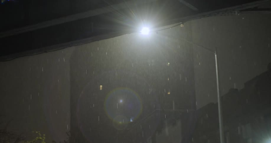 A street light illuminates rain falling in a downtown area
