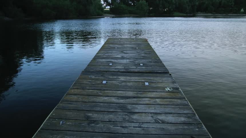 Old wooden dock in lake at dusk