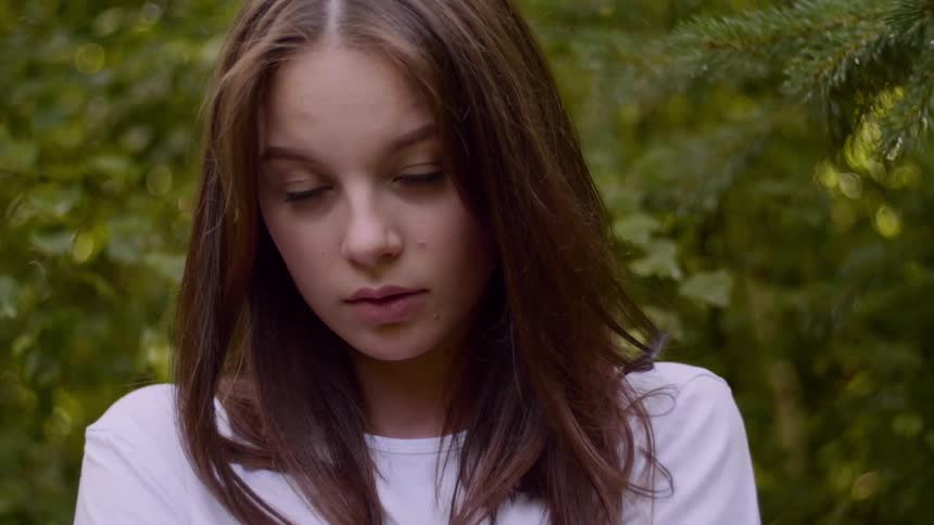 Close up of a long haired young woman near the trees