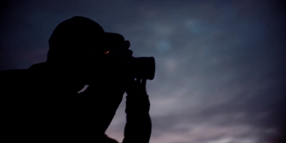 Photographer with a camera taking pictures at sunset