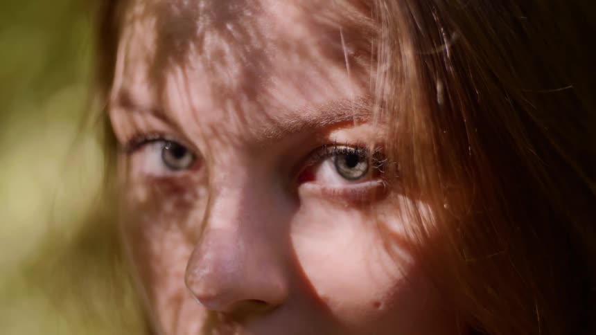 Sunlight filters through foliage to illuminate a teenage girl